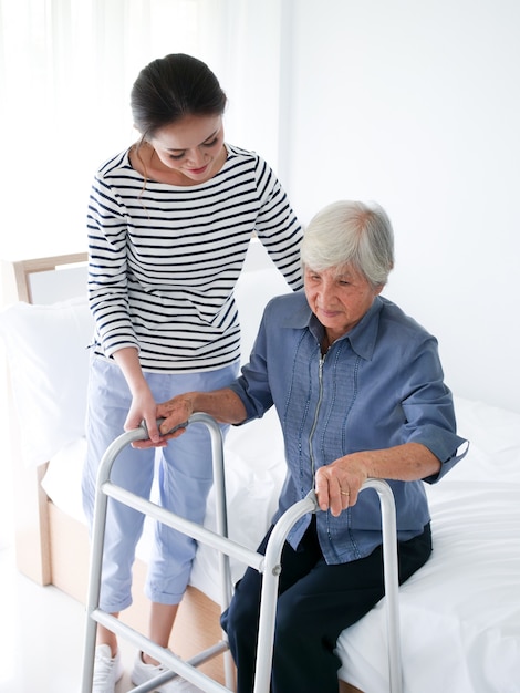 Tochter, die ihrer Mutter verwendet Wanderer im Schlafzimmer hilft.