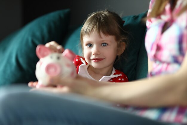 Tochter legte Geld in Sparschwein Mutter hält es in der Hand.