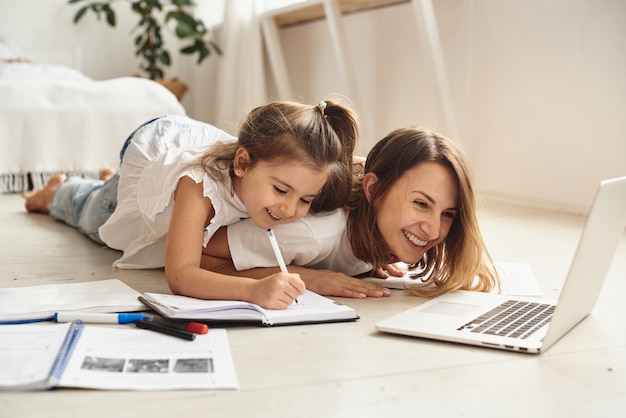 Tochter spielt mit Mama und Katze, während Mama am Computer arbeitet