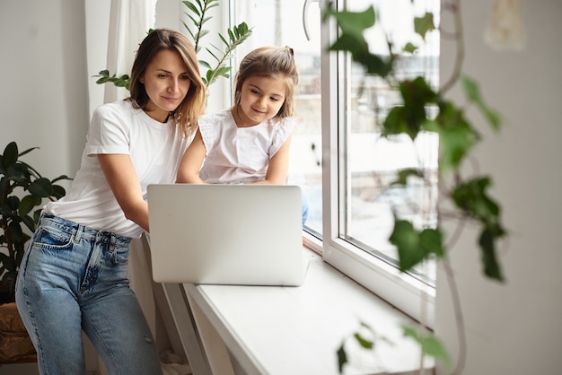Tochter spielt mit Mutter und Katze, während Mutter am Computer arbeitet