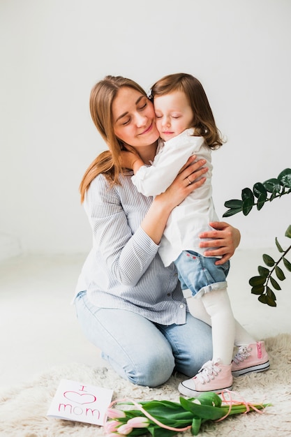 Tochter und Mutter, die nahe Grußkarte umarmen