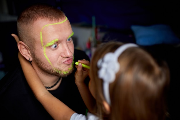 Tochter und Vater malen ein Gesicht und haben Spaß