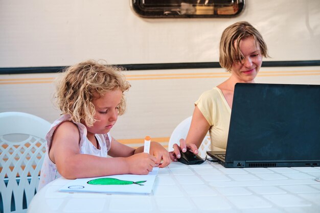 Foto tochter zeichnet, während mutter in den ferien auf einem campingplatz arbeitet