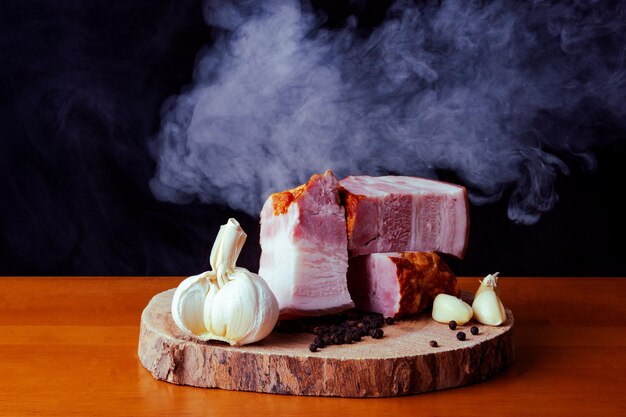 Foto tocino con carne con cuchillo en la tabla de cortar de madera con fondo negro