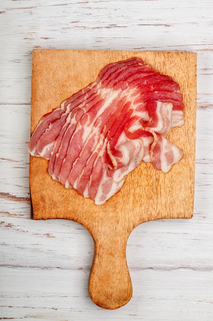 Tocino crudo ahumado en una tabla de cortar