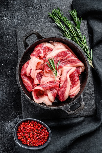 Tocino crudo, tiras de carne veteada en una sartén