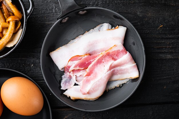 Tocino fresco en rodajas frío, sobre mesa de madera negra