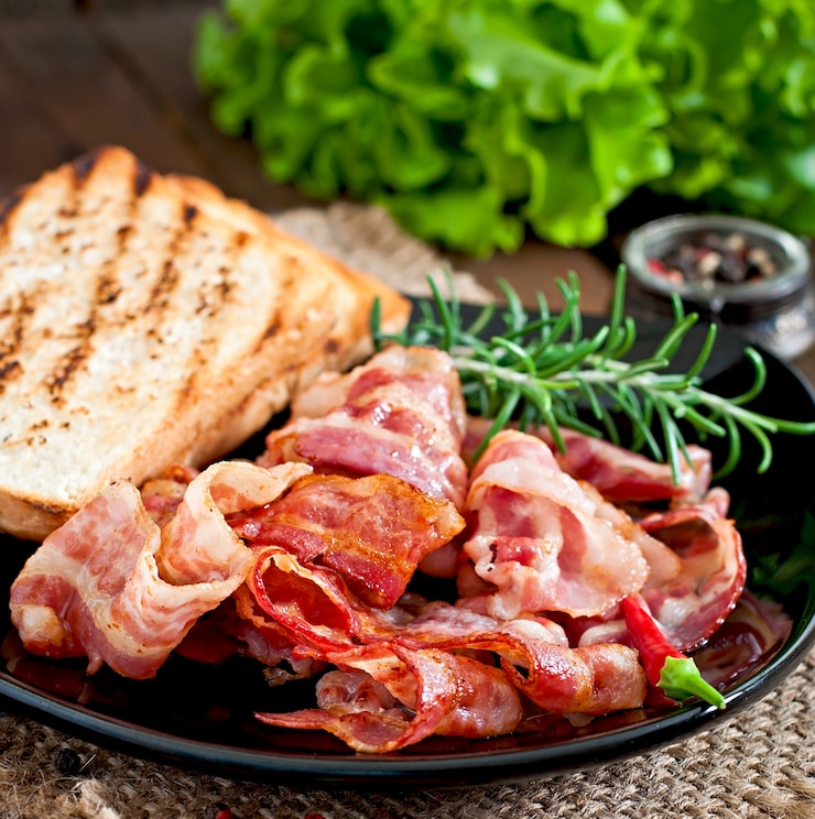 Foto tocino frito y tostadas en un plato negro