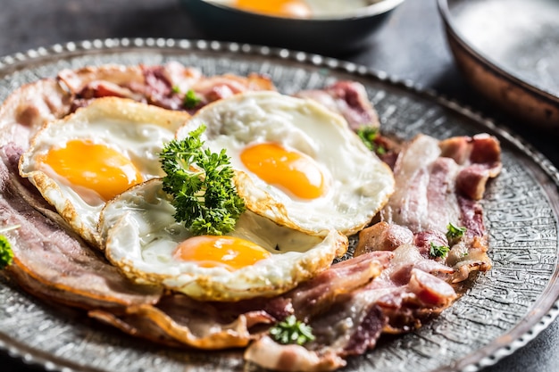 Tocino y huevo asados del primer con las hierbas en la placa.