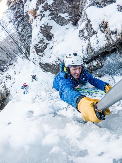 Toda la longitud desde arriba de un montañero escalando hielo con nieve