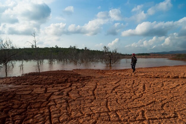 Toda la longitud del hombre por el río en el campo agrietado