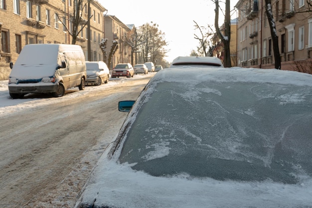 Todas las ventanillas de los coches aparcados están cubiertas de nieve y hielo Escarcha en el parabrisas en invierno Grandes heladas y nevadas en la ciudad Problemas en carreteras resbaladizas en invierno