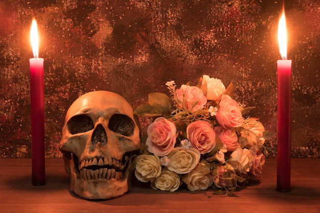 Todavía fotografía de la pintura de la vida con el cráneo, la rosa y la vela humanos en la tabla de madera