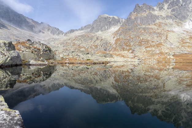 Todavía lago alpino que refleja montañas rocosas con colores de otoño que lo rodean Eslovaquia Europa