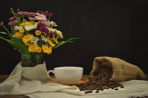 Foto todavía vida con una taza de café en el platillo de madera y el grano de café en saco de la arpillera.