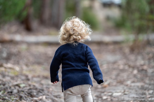 Todder rubio caminando en un bosque en una caminata