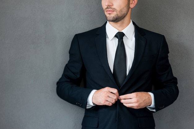 Todo debería estar perfecto. Imagen recortada del joven empresario seguro ajustando su chaqueta