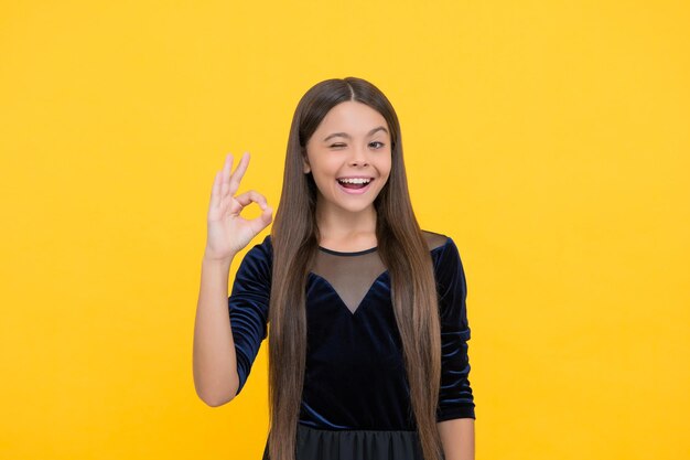 Todo es genial Niño feliz mostrar OK fondo amarillo Aspecto fresco de niña Peluquería Estilo de moda Ropa de moda para niños Día del niño