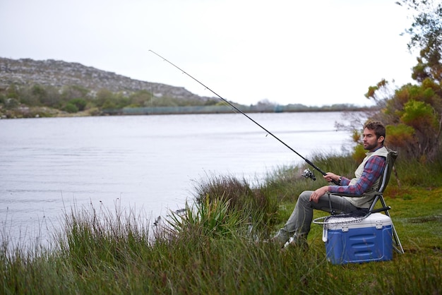 Todo está tranquilo junto al lago Captura de un apuesto joven pescando junto a un lago