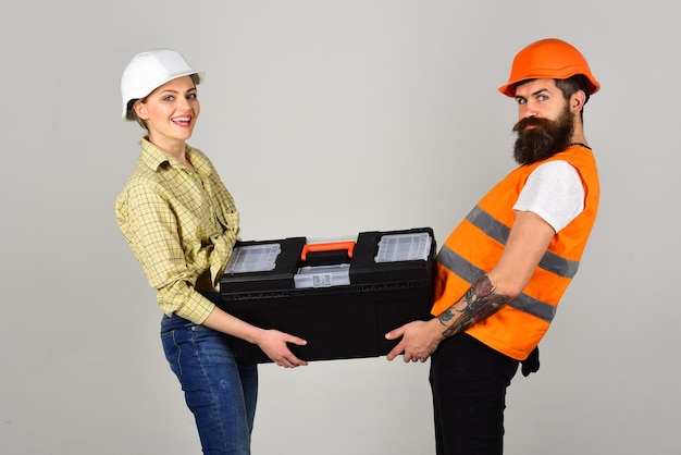 Todo lo que es nuestro lo llevamos con nosotros Pareja de trabajadores de la construcción Constructores o técnicos de construcción sostienen un kit de reparación Pareja de trabajadores duros Mujer bonita e hipster en ropa de trabajo En construcción