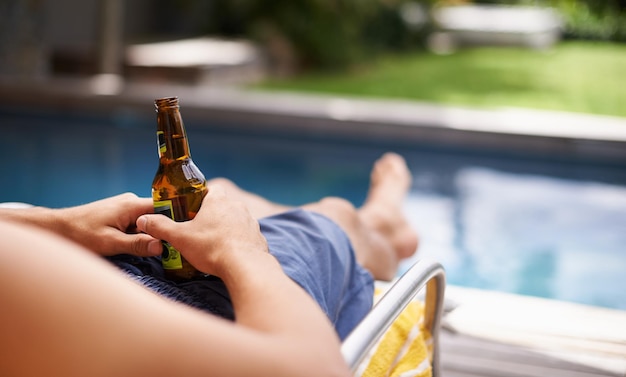 Todo lo que necesitas para refrescarte este verano Captura recortada de un hombre sosteniendo una cerveza junto a la piscina