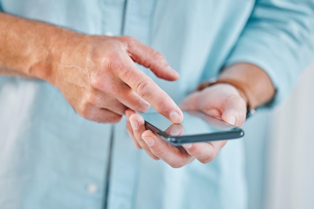 Todo lo que necesito saber está en Internet Captura recortada de un hombre de negocios irreconocible parado solo en su oficina y usando su teléfono celular