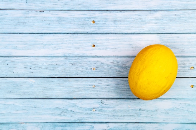 Todo un melón amarillo se encuentra sobre un fondo de madera azul.Concepto de verano