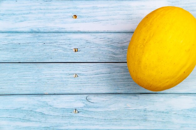 Todo un melón amarillo se encuentra sobre un fondo de madera azul.Concepto de verano