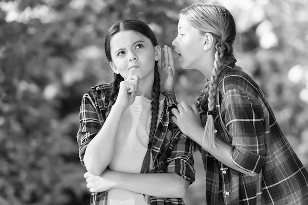 Todo el mundo sabe que Chatear chicas verano al aire libre Niño pequeño susurrar noticias en el oído de un amigo Alto secreto Escuchar todas las charlas y chismes Chismear y hablar Comunicación entre amigos