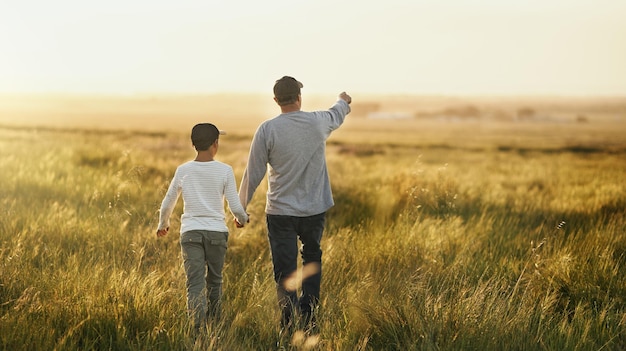 Todo esto será tuyo, hijo Toma de un hombre que lleva a su hijo a dar un paseo por un campo abierto