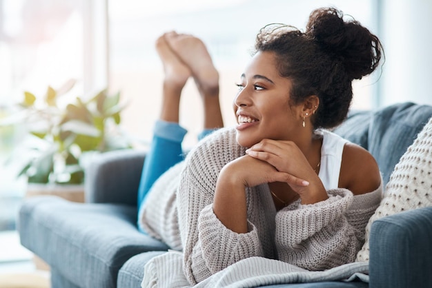 Todo a su alrededor la hace feliz Toma completa de una joven feliz relajándose en su sofá en casa