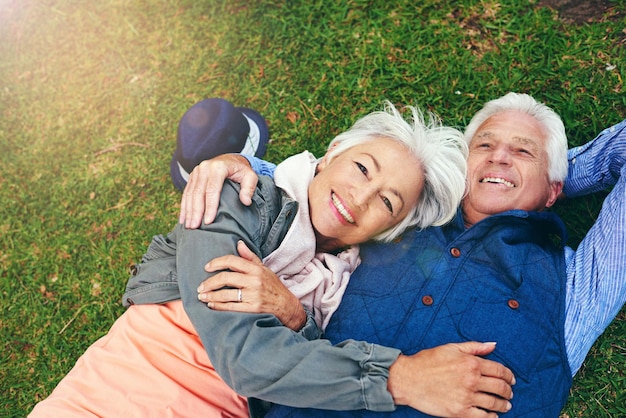 Todos los días me enamoro de él de nuevo Retrato de una feliz pareja de ancianos recostada en el césped juntos en el parque