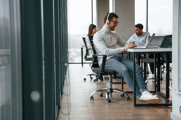 Todos estão a usar laptops. Homens e mulheres estão a trabalhar juntos no escritório.