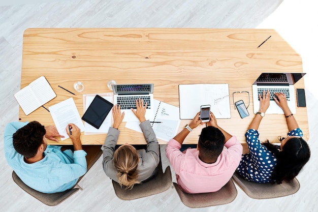 Todos estão muito ocupados neste espaço de trabalho compartilhado Foto de alto ângulo de um grupo de empresários trabalhando juntos em uma mesa em um escritório