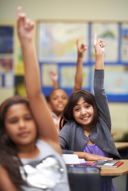 Todos saben la respuesta Un grupo de estudiantes levantando la mano en clase