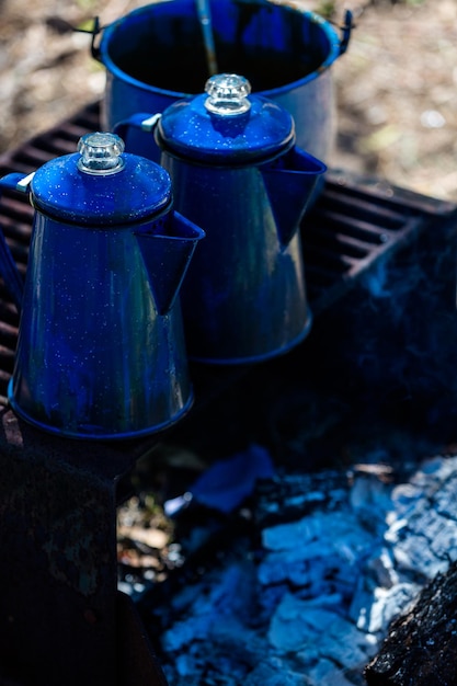 Töpfe kochendes Wasser auf Campingfeuerstelle mit Holz.