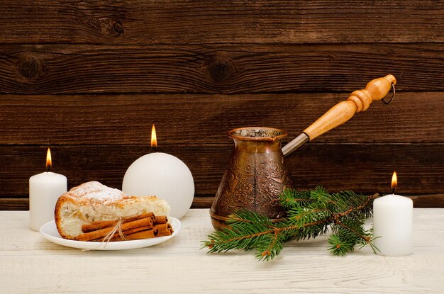 Foto töpfe mit kaffeetanne zweig apfelkuchen zimtstangen und kerzen auf dem hölzernen hintergrund