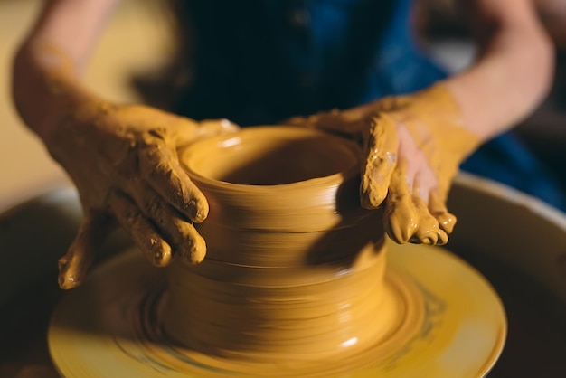 Töpferwerkstatt. Ein kleines Mädchen macht eine Vase aus Ton. Modellieren aus Ton.