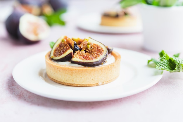 Törtchen Gebäck mit weißer Sahne, garniert mit Feigen und Pistazien Kochkonzept Gesundes Dessert