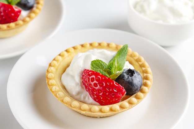 Törtchen mit Beeren auf einer weißen Hintergrundnahaufnahme