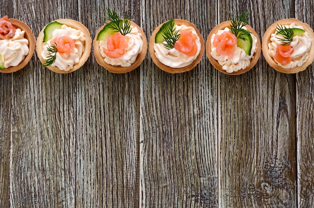 Törtchen mit Frischkäse und gesalzenem Lachs auf Holzhintergrund. Leckerer leichter Snack für eine Party. Fingerfood. Die Draufsicht mit Kopierbereich