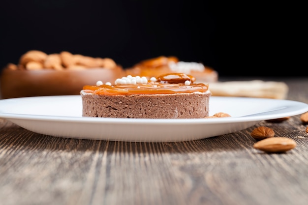 Törtchen mit Milchkäsefüllung und viel Salzkaramell mit Nüssen, Mandeln auf Törtchen mit Hüttenkäse oder Buttercreme und Karamell, leckere Desserts