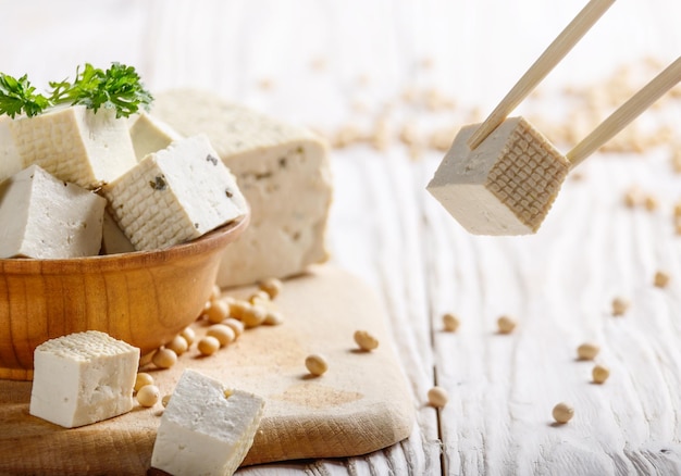 Tofu aus Sojabohnenquark in Holzschale auf weißem Küchentisch aus Holz Nondairy Alternative Ersatz für Käse Platz für Text