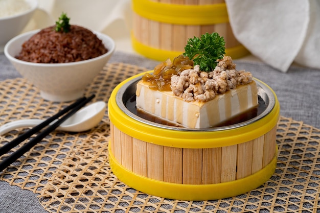 TOFU COZIDO NO VAPOR Com CARNE DE PORCO PICADA e ALFACE EM PICLETO com pauzinhos servido em prato isolado em cima da mesa vista de comida de singapura