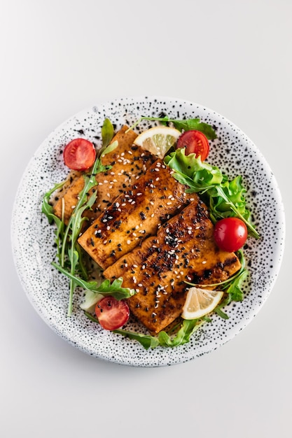 Foto tofu frito em molho de soja com tomate cereja, alface, limão e sementes de gergelim