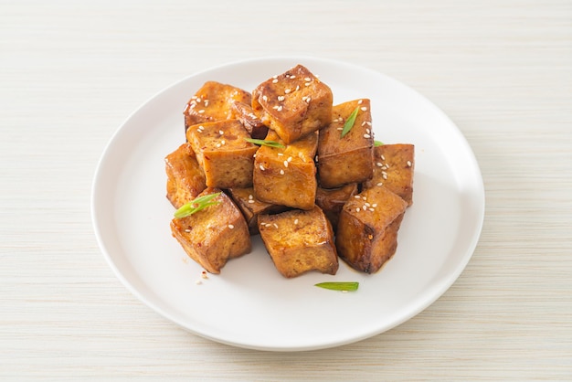 tofu frito con sésamo blanco y salsa teriyaki - estilo de comida vegana y vegetariana