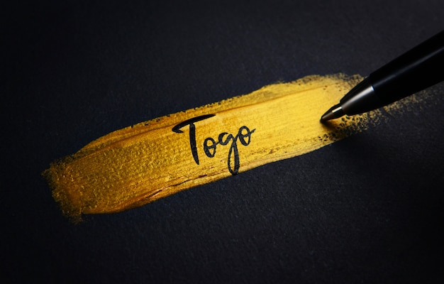 Togo texto manuscrito em pincelada de tinta dourada