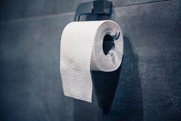 Toilettenpapier auf anthrazit gefliester Wand Rolle Toilettenpapier auf einem Hintergrund