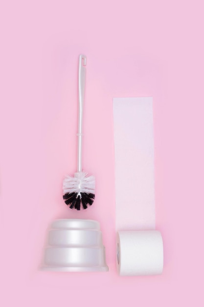 Toilettenpapier und Toilettenbürste auf rosa Hintergrund