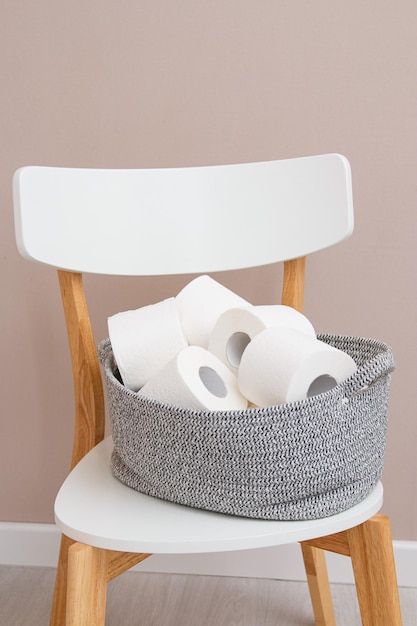 Toilettenpapierrollen in einem gestrickten Korb auf einem weißen Stuhl